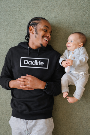 Een jonge vader die met zijn pasgeboren kindje samen op de grond ligt