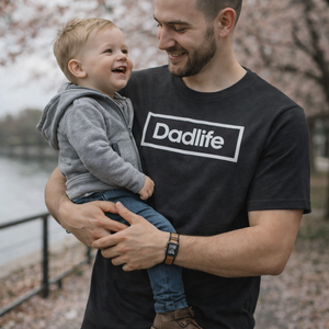 Jonge vader die een grijs dadlife tshirt draagt, terwijl hij zijn zoontje draagt