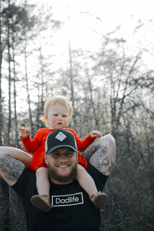 Trotse vader in de natuur die een zwart dadlife tshirt draagt